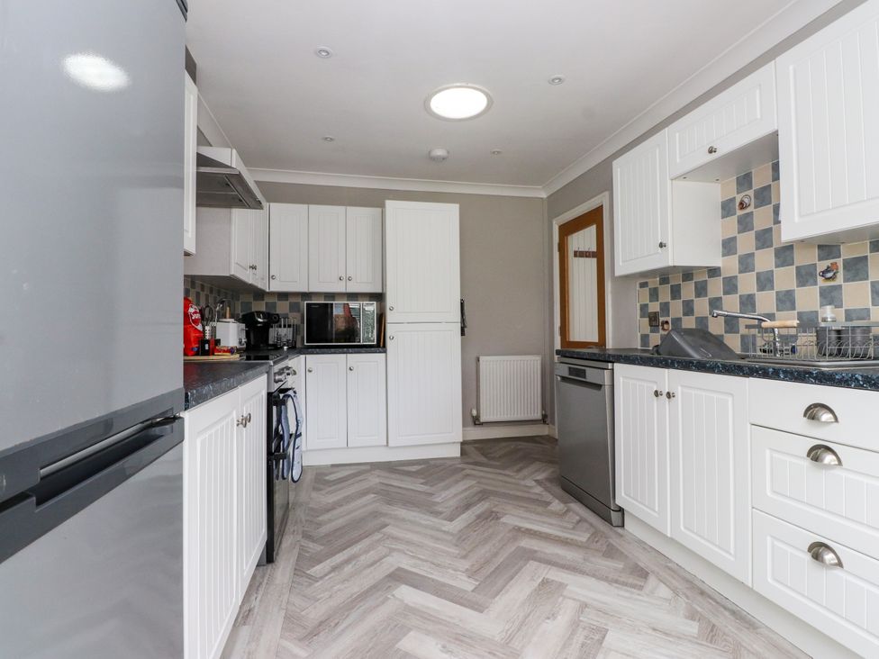 A kitchen with appliances and cabinets at 3 Tai Newydd Llanfaelog near Rhosneigr