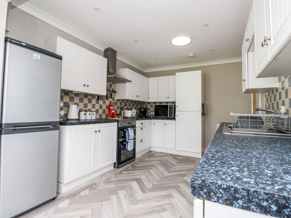 A kitchen with cabinets, refrigerator, oven, and sink at 3 Tai Newydd Llanfaelog near Rhosneigr