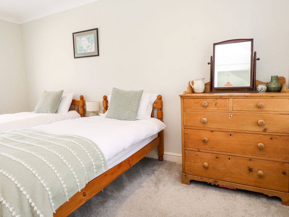A bedroom with two beds and a dresser at 3 Tai Newydd Llanfaelog near Rhosneigr