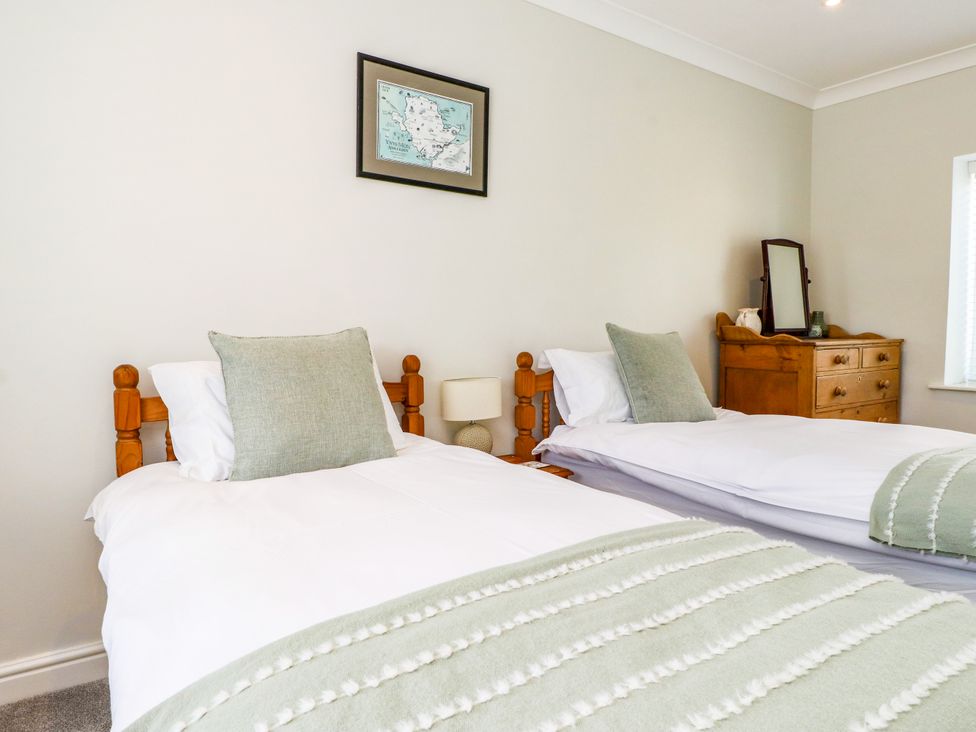 A bedroom with two beds and a dresser at 3 Tai Newydd Llanfaelog near Rhosneigr