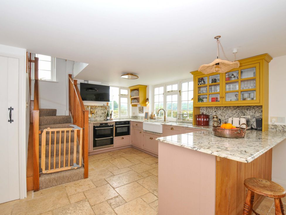 A kitchen with cabinets and a staircase at Island House in Golant near Tywardreath