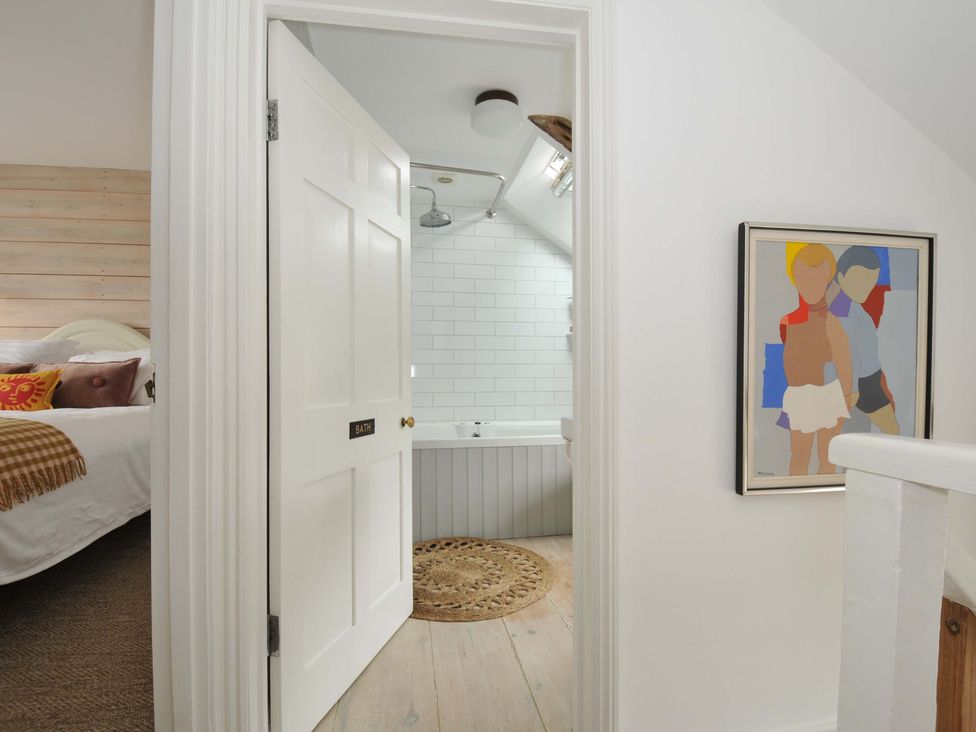 A bathroom with a bathtub visible through a door at Island House Golant near Tywardreath