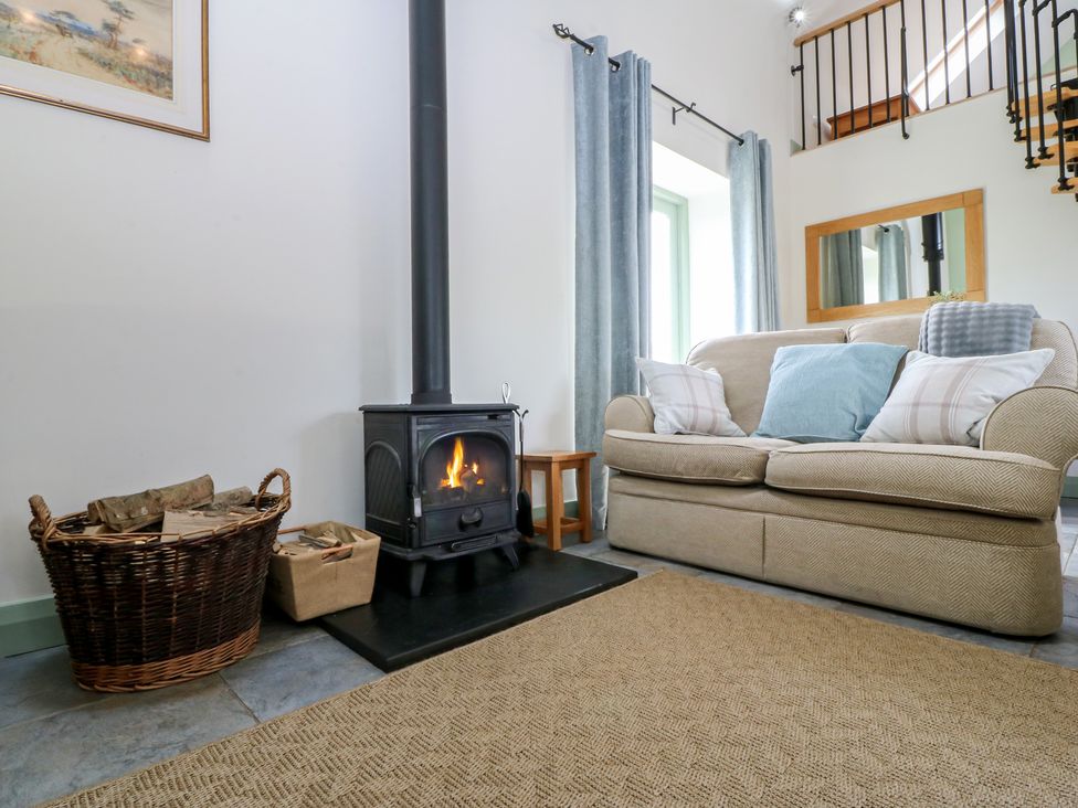 A living room with a sofa and a stove at No 1 The Granary in Capel Coch near Llannerch-Y-Medd