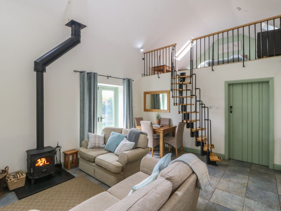 A living room with a wood stove and staircase at No 1 The Granary Capel Coch near Llannerch-Y-Medd