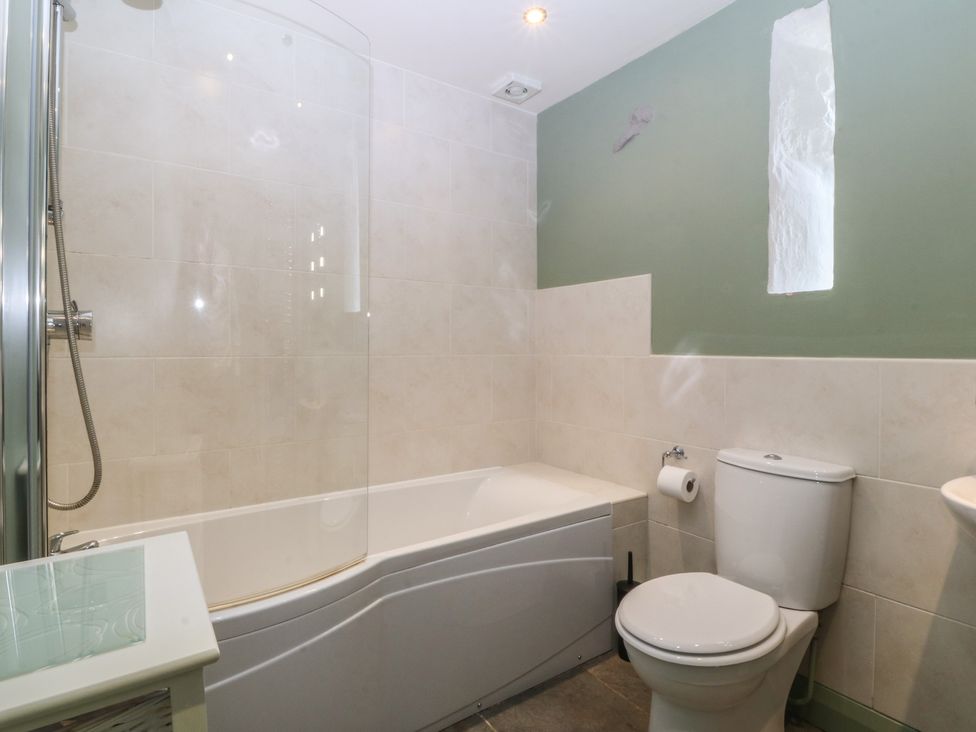 A bathroom with a bathtub, shower, toilet, and sink at No 1 The Granary in Capel Coch near Llannerch-Y-Medd