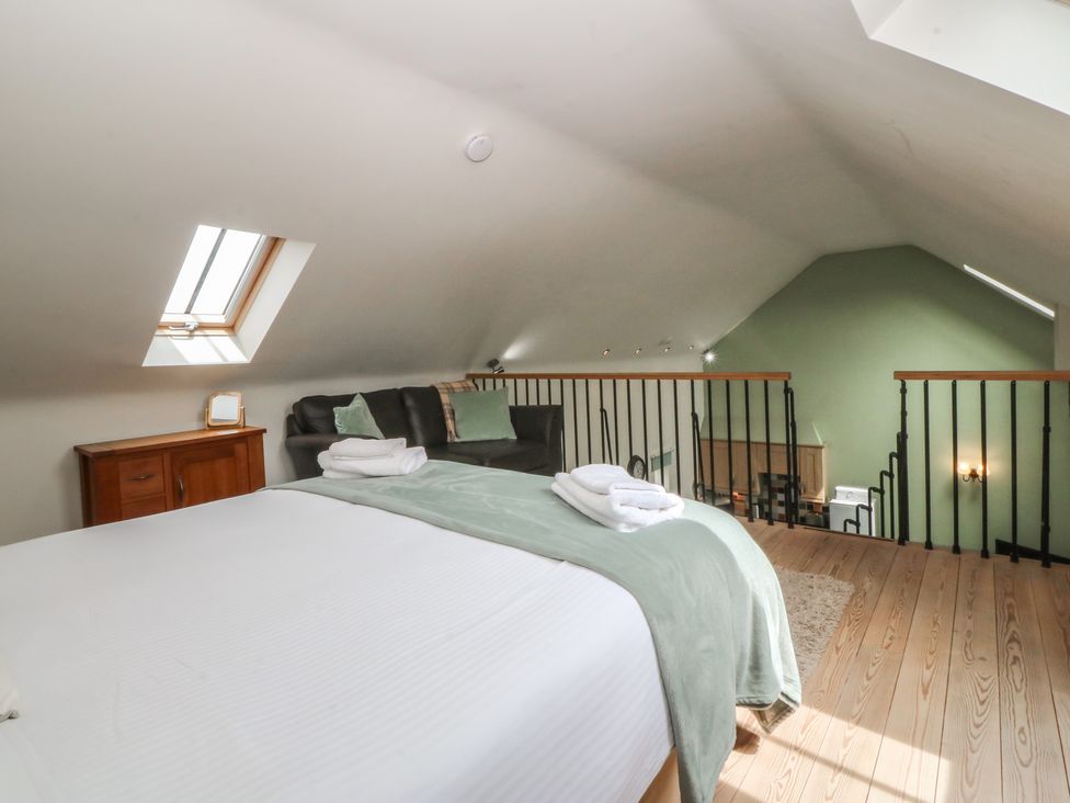A loft with a bed and sofa at No 1 The Granary in Capel Coch near Llannerch-Y-Medd