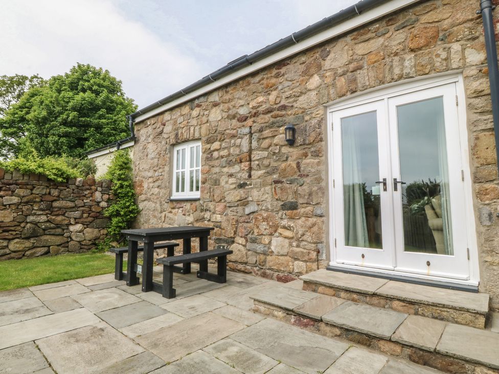 A patio area with a table and stone wall at No 1 The Granary Capel Coch near Llannerch-Y-Medd