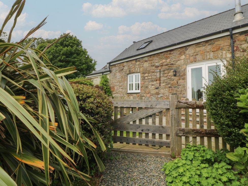 An entrance with a stone wall and wooden gate at No 1 The Granary in Capel Coch near Llannerch-Y-Medd