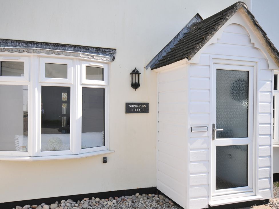 An exterior view of Shrimper's Cottage featuring a sign and windows in Tredrizzick near St Minver