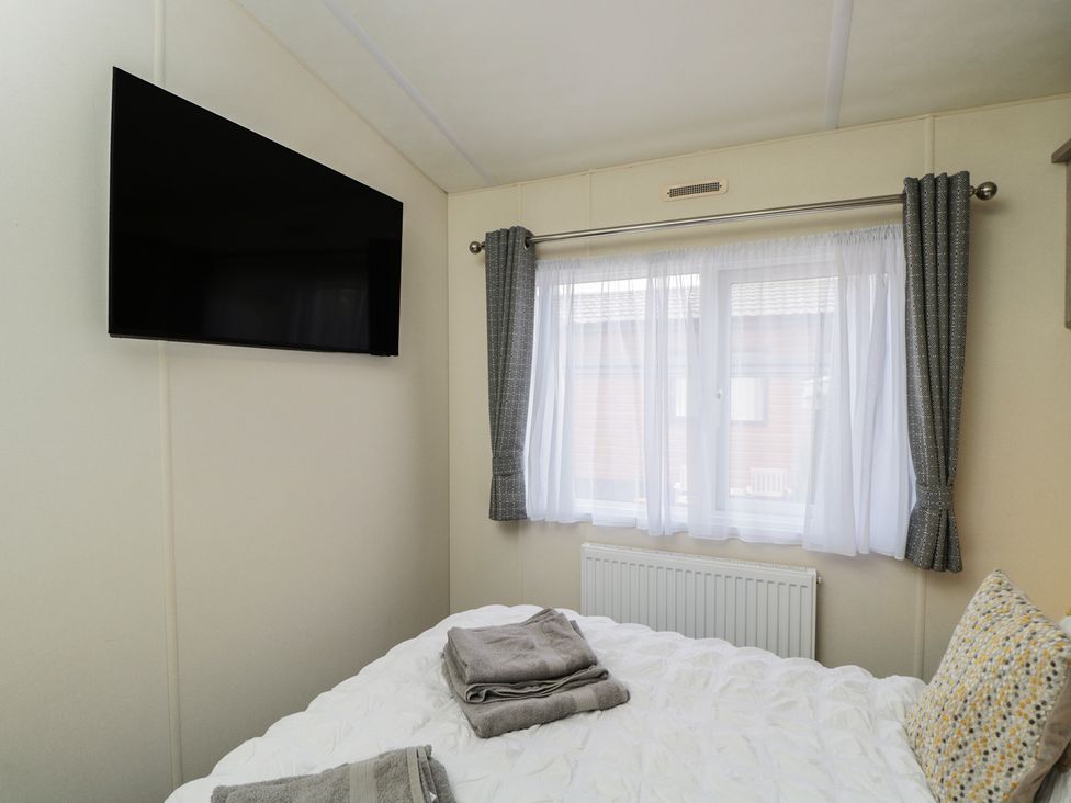 A bedroom with a TV, bed, and window at The Cotswold Holiday Lodge in Evesham