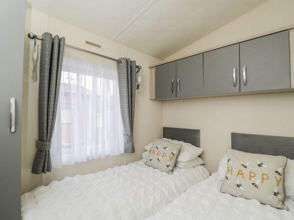 A bedroom with a bed and pillows at The Cotswold Holiday Lodge in Evesham