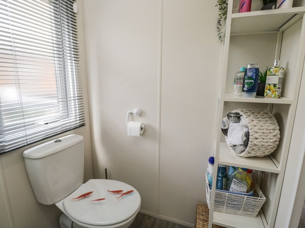 A bathroom with a toilet and shelves at The Cotswold Holiday Lodge in Evesham