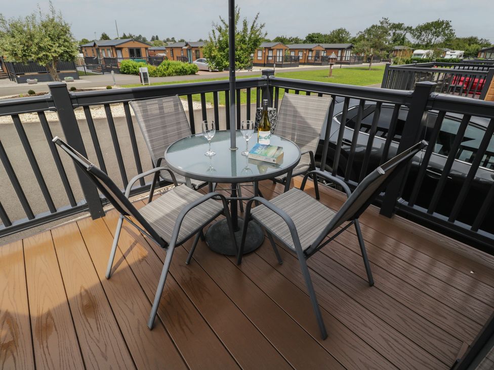 A table with chairs and drinks on a patio at The Cotswold Holiday Lodge in Evesham