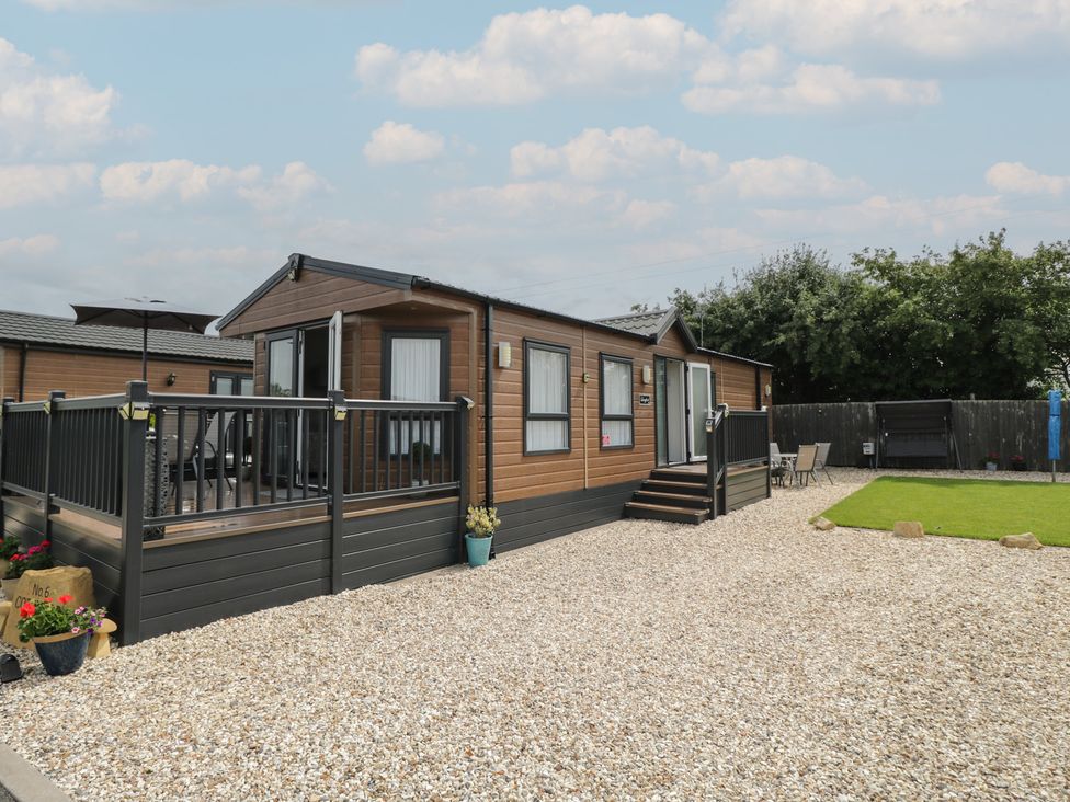 A mobile home with a deck and lawn at The Cotswold Holiday Lodge in Evesham