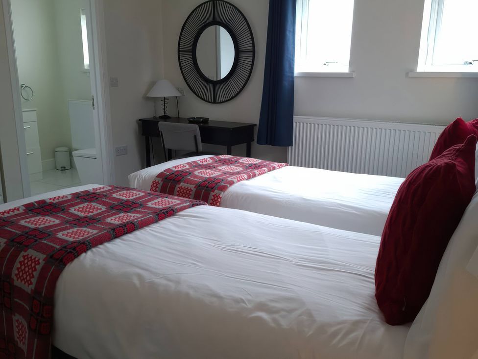 A bedroom with twin beds and a desk at Teifi Villa in St Dogmaels