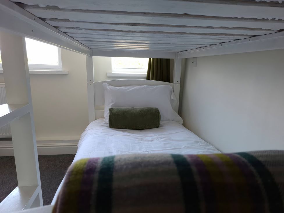 A bed with pillow and cushion under a loft bed at Teifi Villa in St Dogmaels