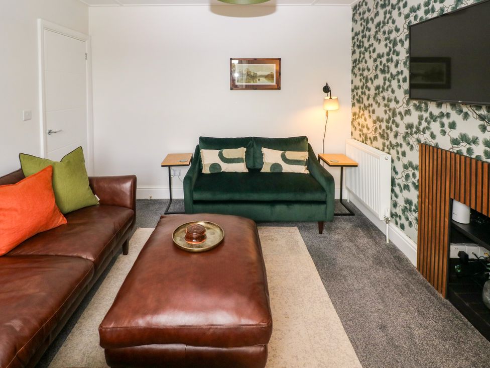 A living room with a green sofa and coffee table at Teifi Villa in St Dogmaels