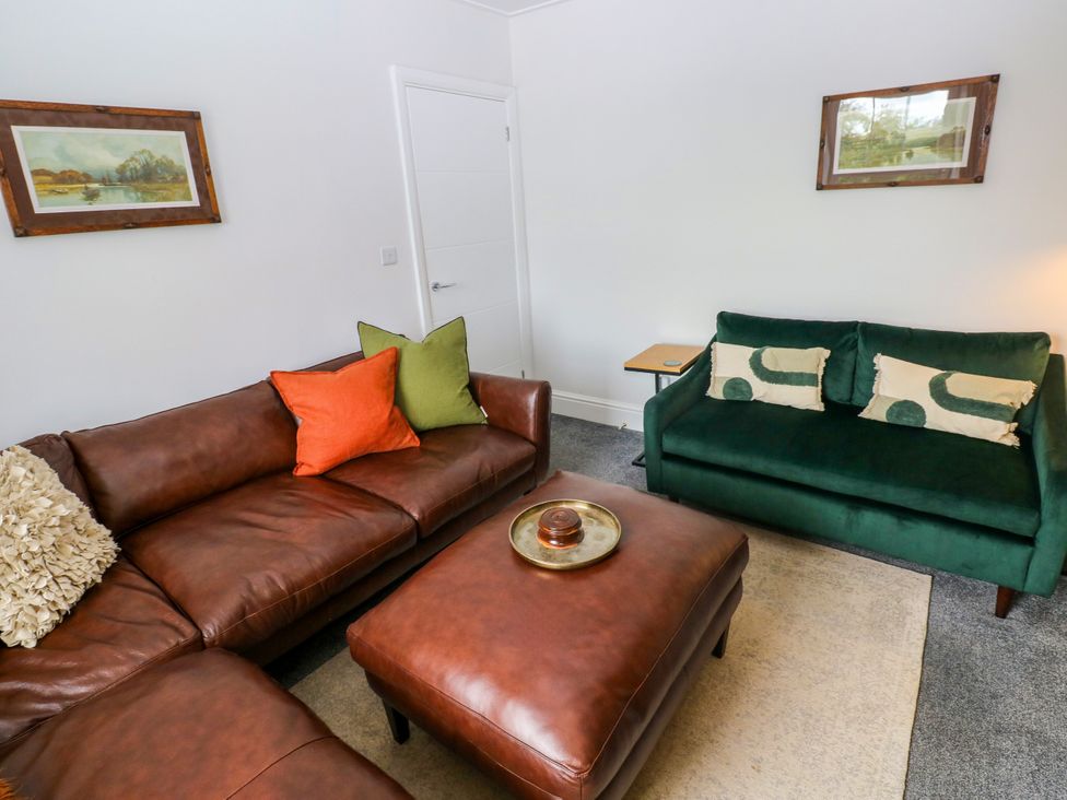 A living room with a brown leather sofa and green sofa at Teifi Villa in St Dogmaels