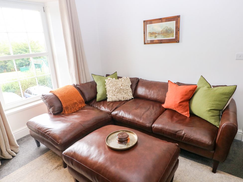 A living room with a brown leather sofa and pillows at Teifi Villa in St Dogmaels