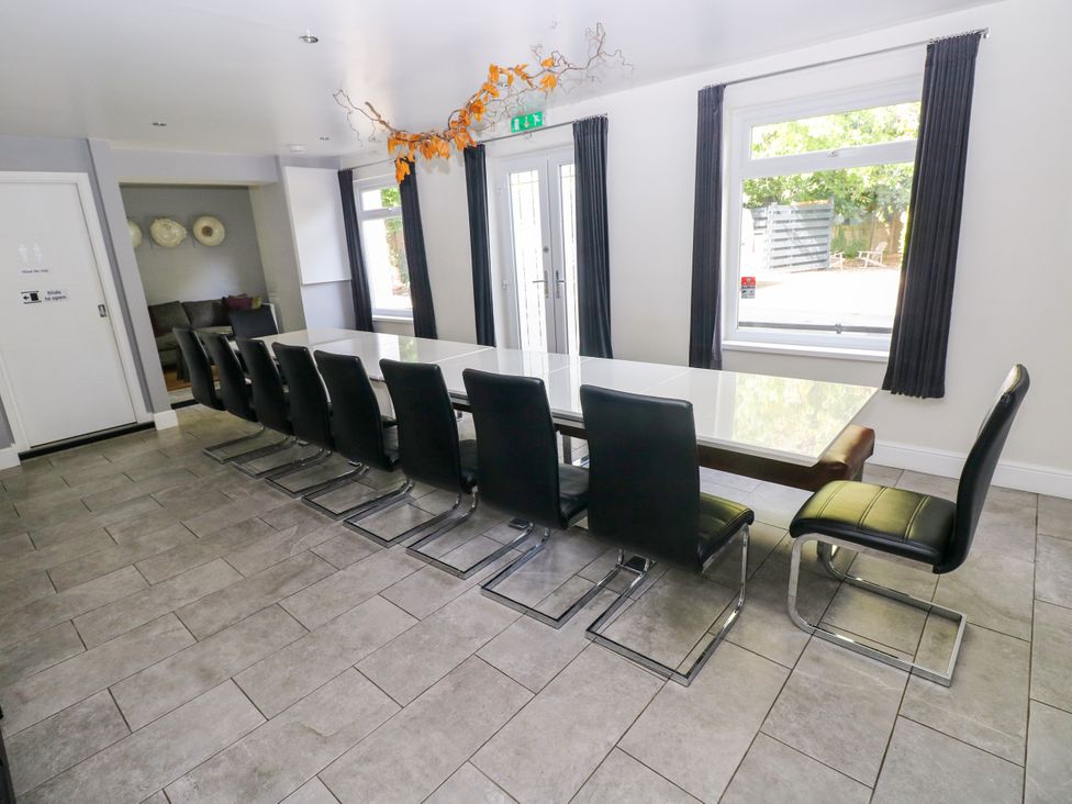 A dining room with a long table and chairs at Teifi Villa in St Dogmaels