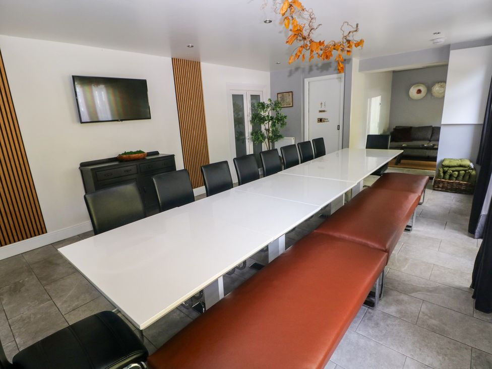 A dining room with a long table and chairs at Teifi Villa in St Dogmaels
