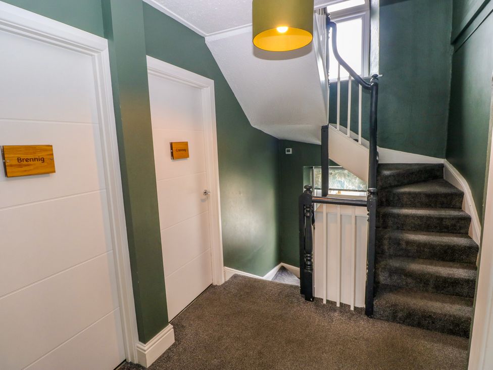 A hallway with doors labeled Brennig and Caerny at Teifi Villa in St Dogmaels