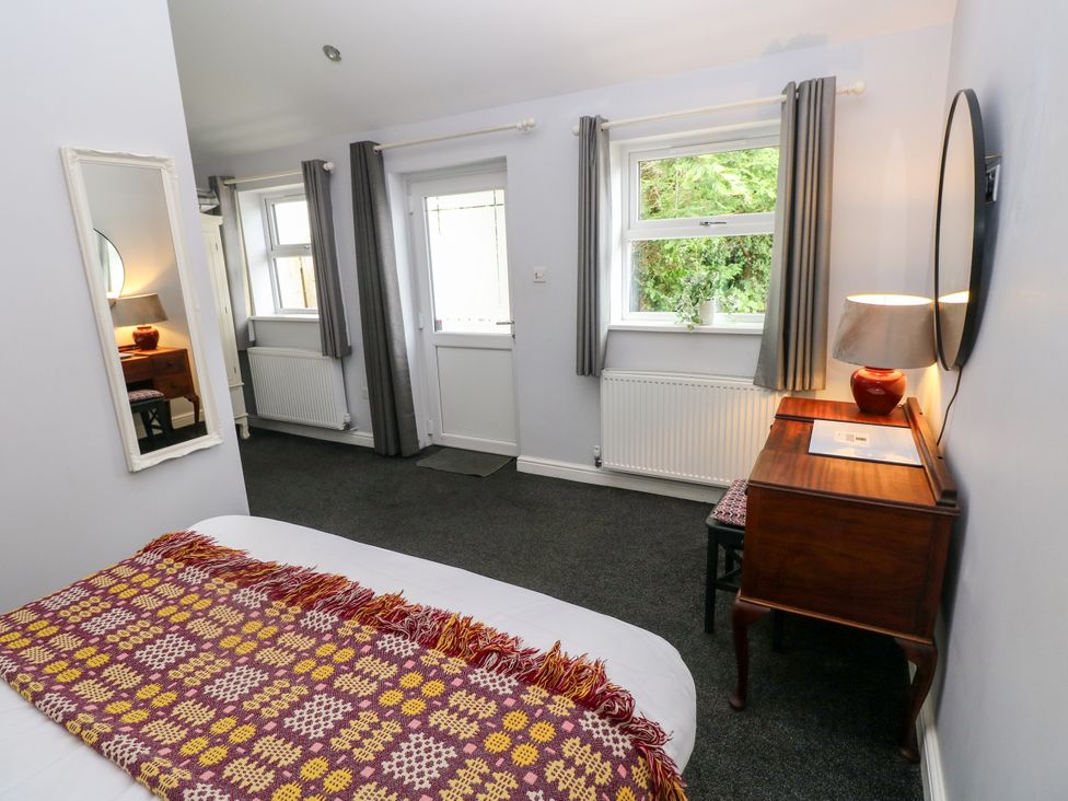 A bedroom with a bed, mirror, desk and chair at Teifi Villa in St Dogmaels