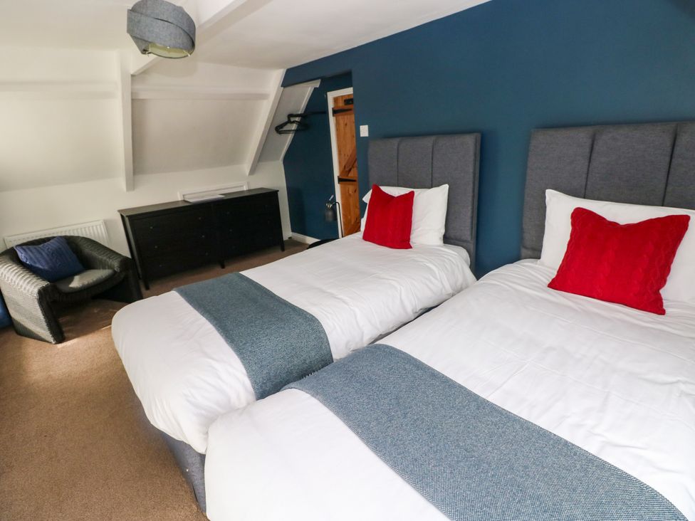 A bedroom with two beds and a chair at Teifi Villa in St Dogmaels