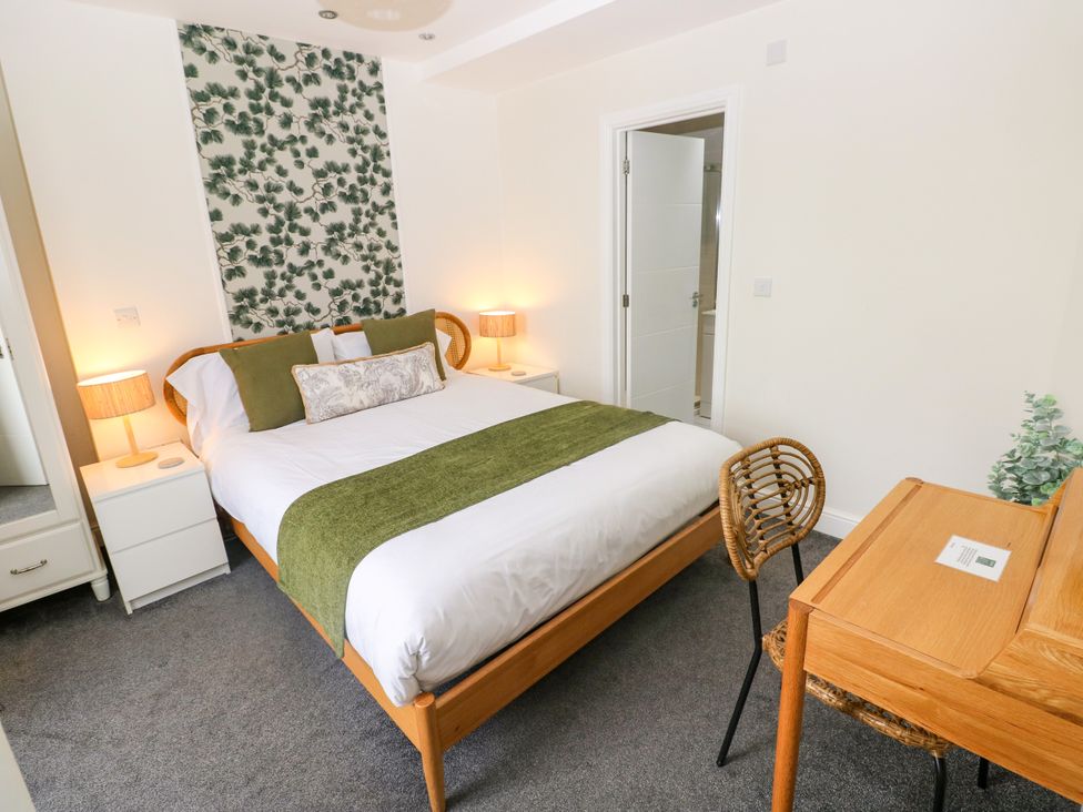 A bedroom with a bed, bedside tables, a desk, and a chair at Teifi Villa St Dogmaels