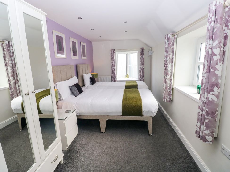 A bedroom with two beds and windows at Teifi Villa in St Dogmaels