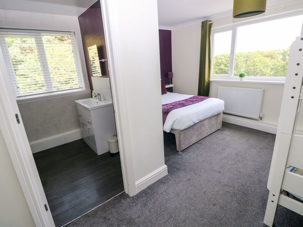 A bedroom with a bed and a bathroom sink at Teifi Villa in St Dogmaels
