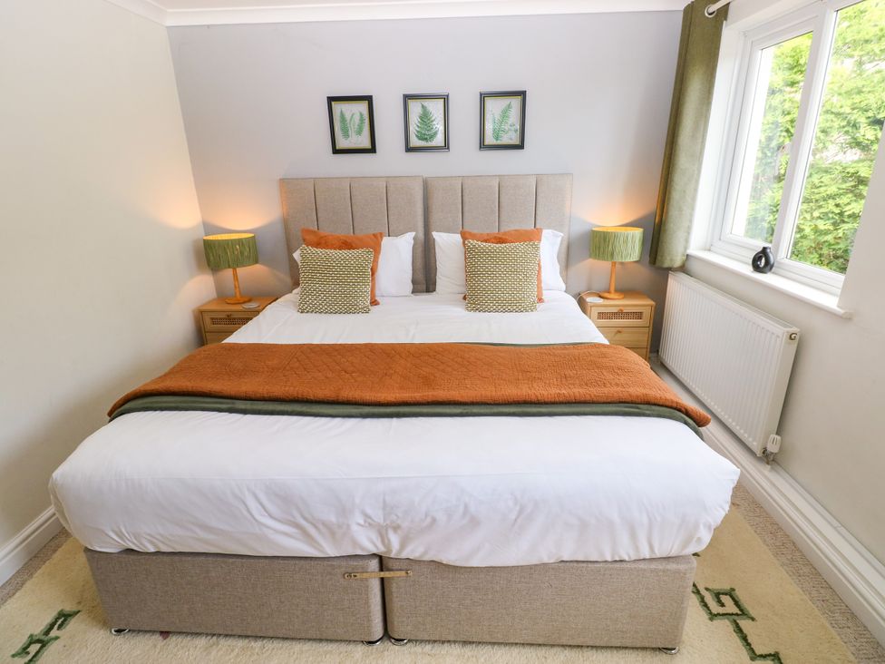 A bedroom with a bed, nightstands, lamps, and a window at Teifi Villa in St Dogmaels
