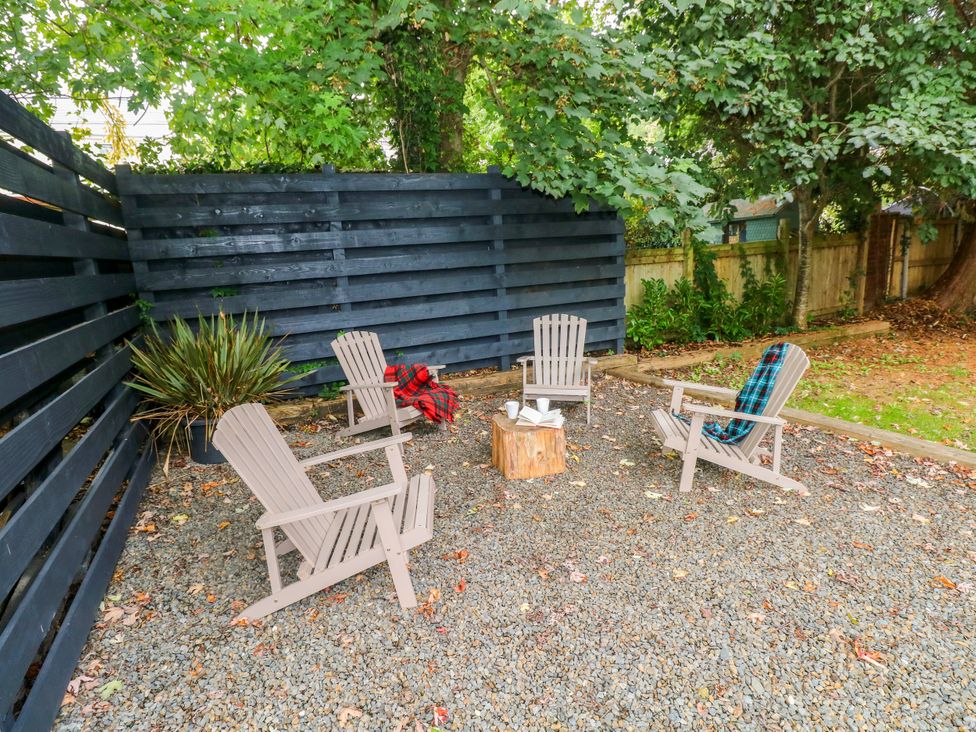 An outdoor seating area with adirondack chairs and a wooden stump at Teifi Villa St Dogmaels