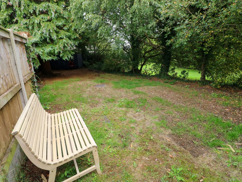 A garden area with a bench and trees at Teifi Villa in St Dogmaels