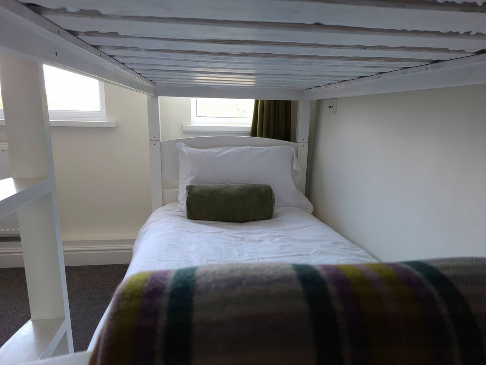 A bed with a pillow and cushion beside a window at Teifi Villa St Dogmaels