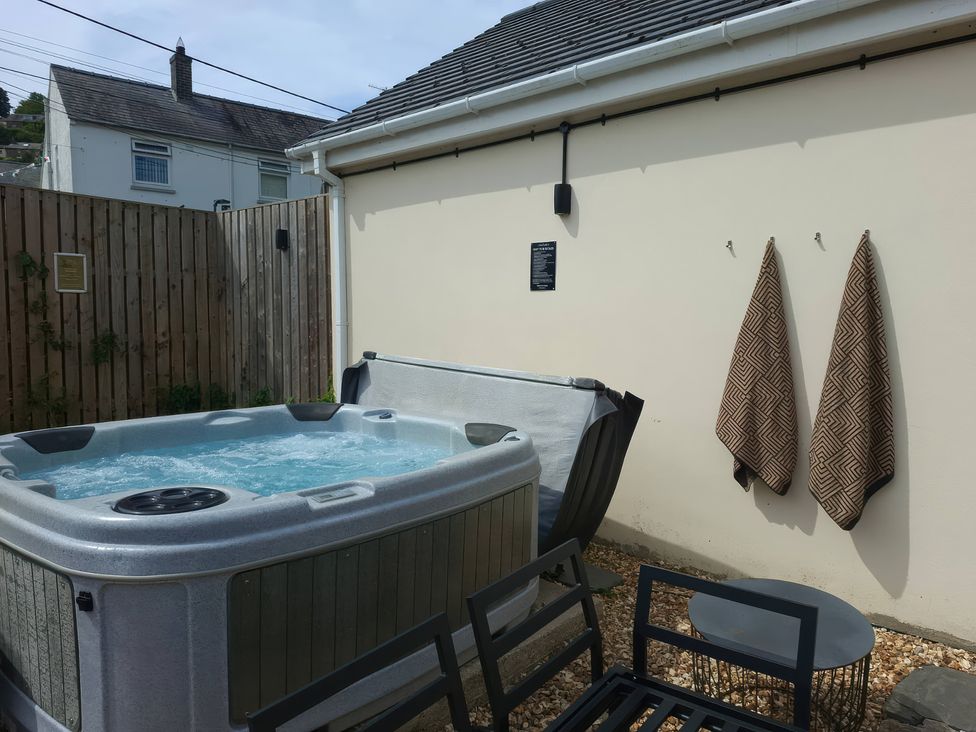 An outdoor area with a hot tub and chairs at Teifi Villa in St Dogmaels