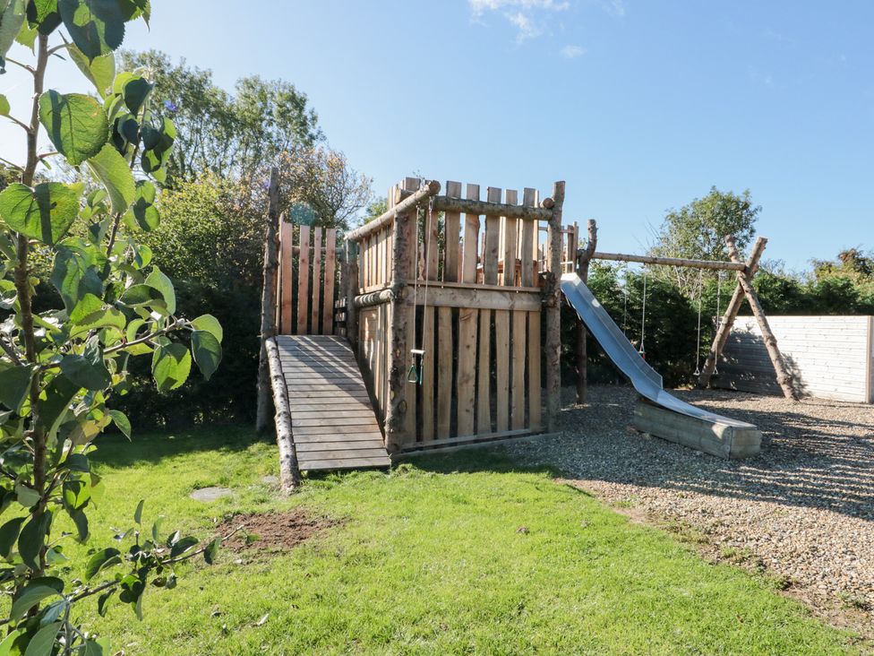 A playhouse with a slide and swing in the garden at Foxes Den in Allerston near Thornton Dale