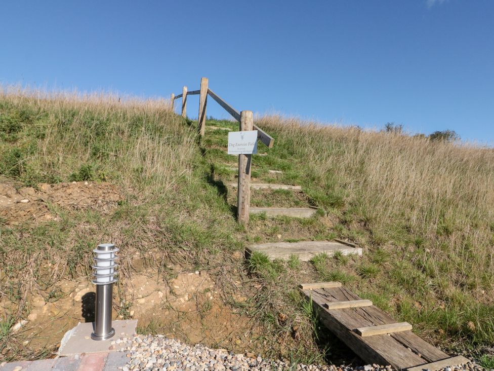 Steps leading to a sign for dog exercise area at Foxes Den Allerston near Thornton Dale