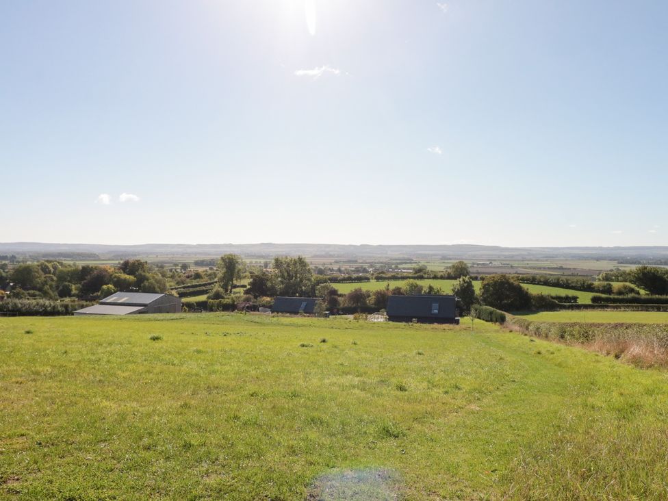 A landscape view with grass, trees and buildings at Foxes Den Allerston near Thornton Dale