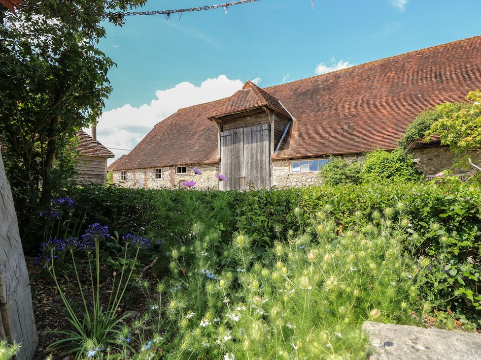 An outdoor view of a barn with plants and flowers at Byre Cottage 4 Sullington near Storrington