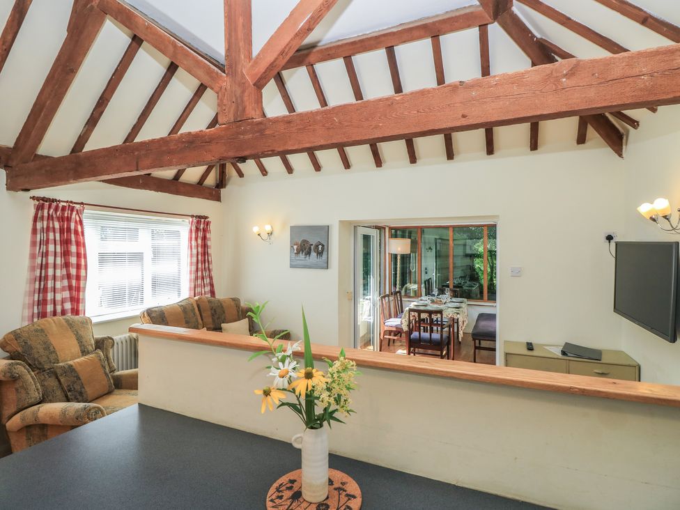 A living room with a sofa and a view into a dining area at Byre Cottage 4 Sullington near Storrington