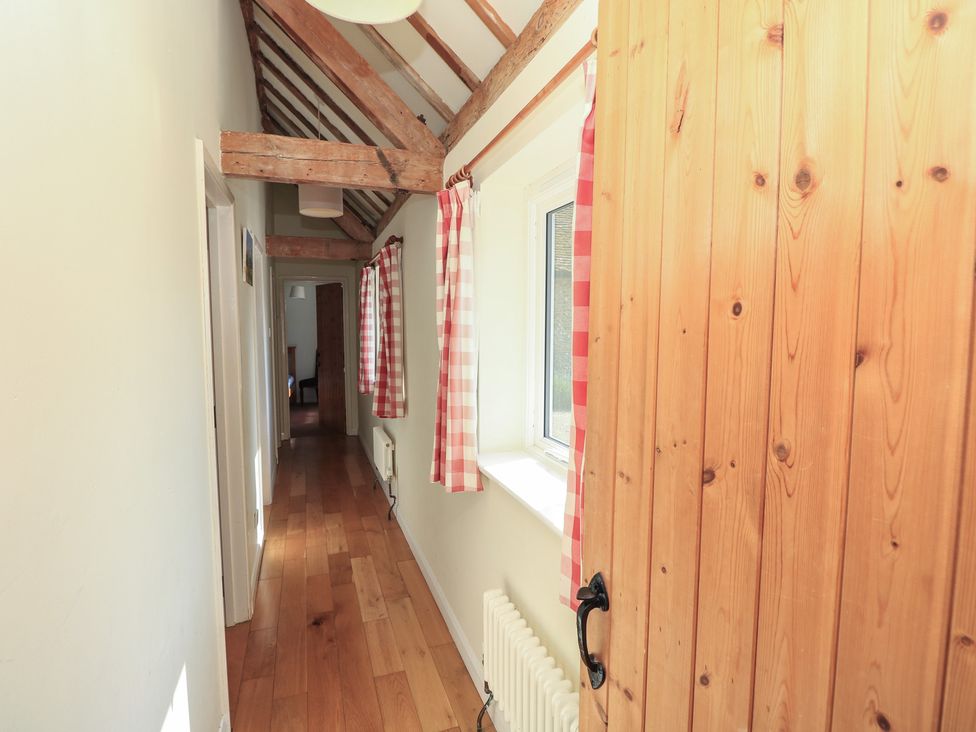 A hallway with wood beams and a door at Byre Cottage 4 Sullington near Storrington