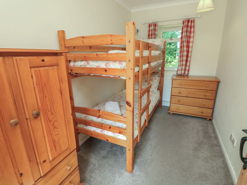 A bedroom with a bunk bed and storage furniture at Byre Cottage 4 Sullington near Storrington