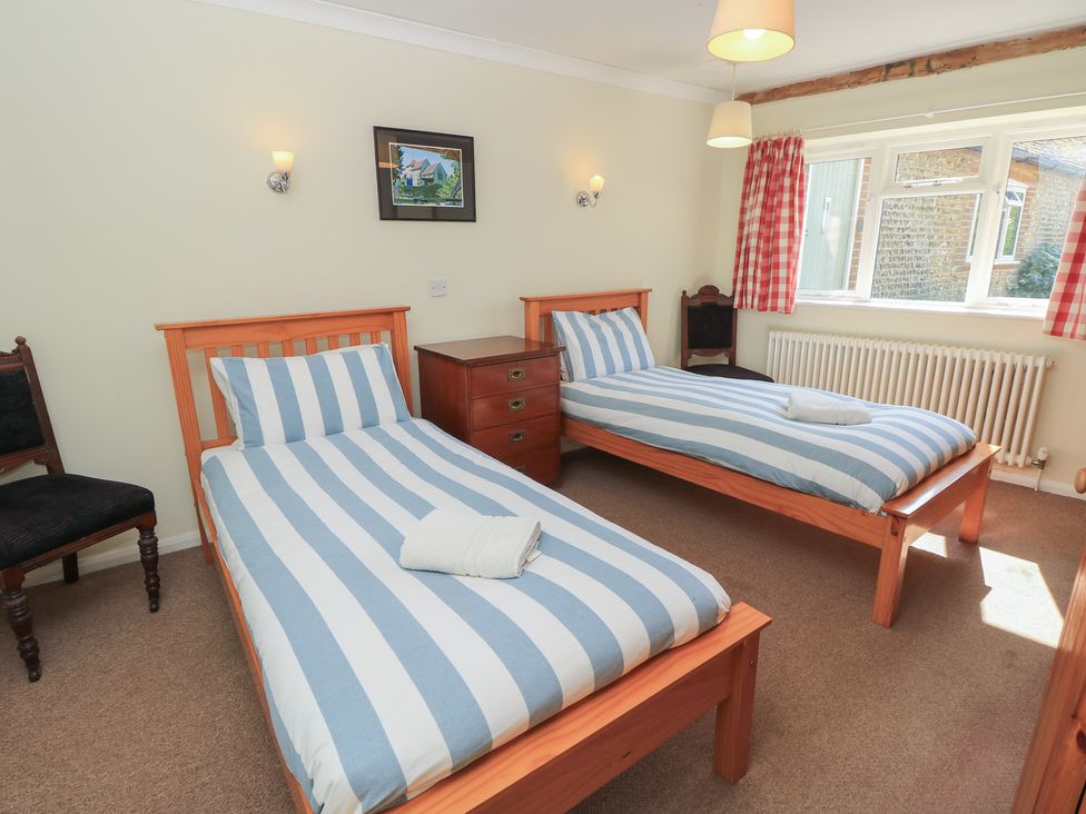 A bedroom with two single beds and a window at Byre Cottage 4 in Sullington near Storrington