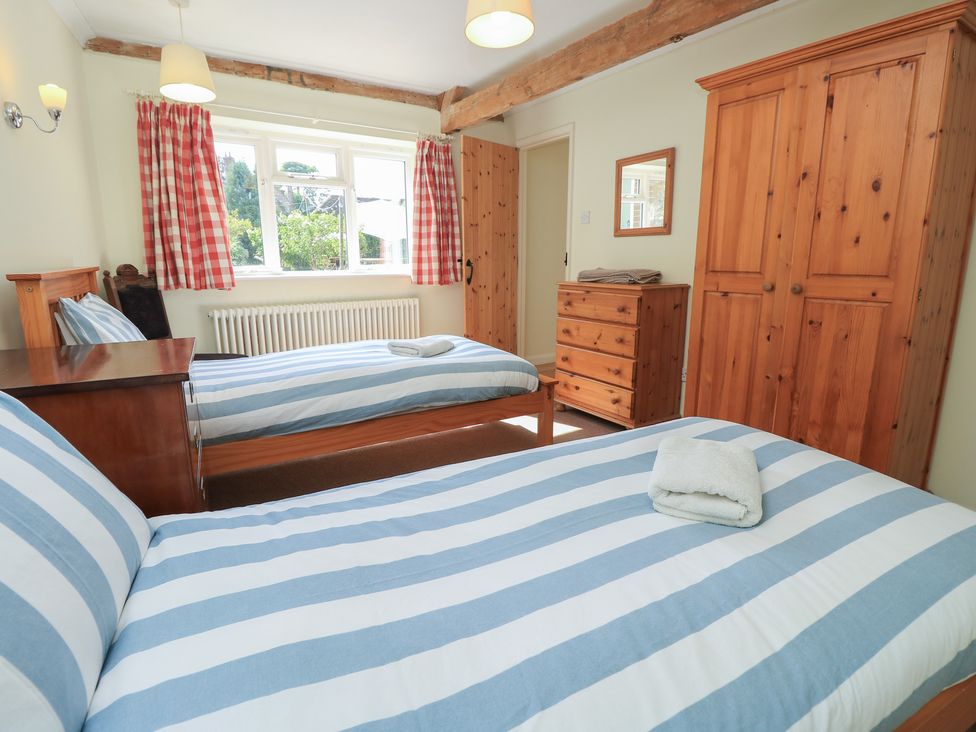 A bedroom with two beds and wooden furniture at Byre Cottage 4 in Sullington near Storrington