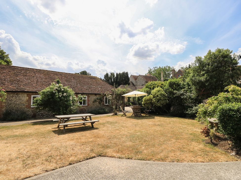 A garden with a picnic table and parasol at Byre Cottage 4 Sullington near Storrington