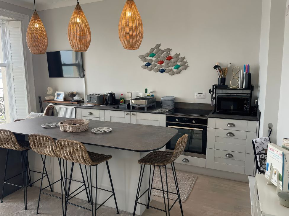 A kitchen with a large island and bar stools at Sunrise Apartment in Weymouth