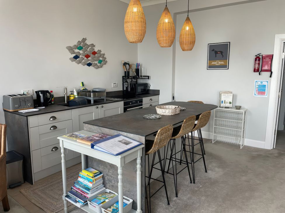 A kitchen with appliances and seating at Sunrise Apartment in Weymouth