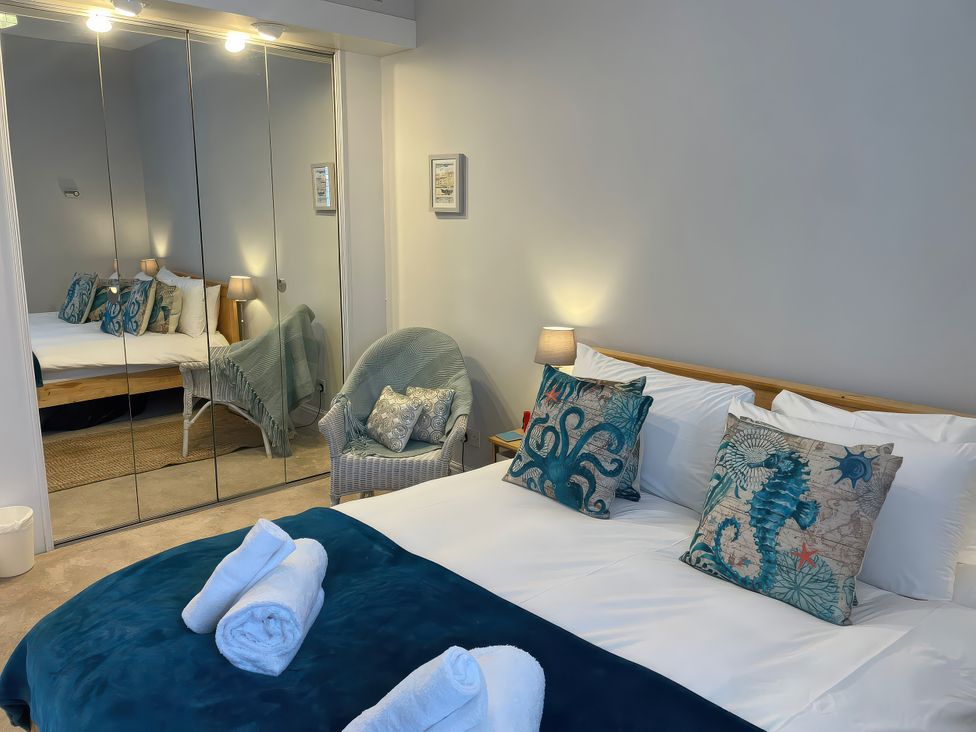 A bedroom with a bed, chair and mirrors at Sunrise Apartment in Weymouth