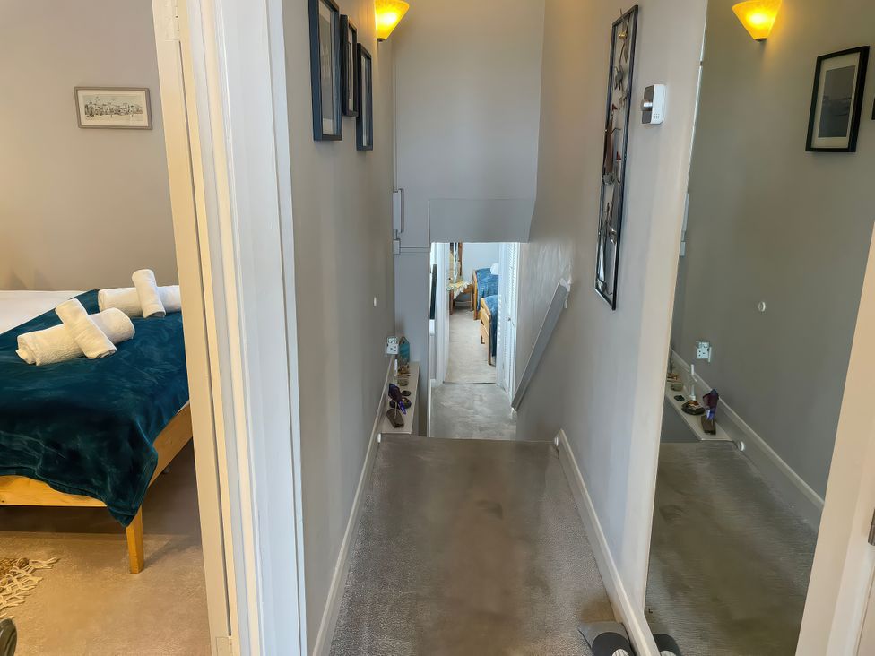 A hallway leading to stairs with a bed visible at Sunrise Apartment in Weymouth